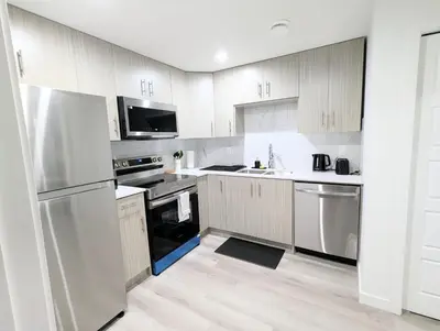 a kitchen with white cabinets and stainless steel appliances at Basement Suite in Desrochers SW in Edmonton