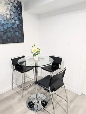 a glass table with four chairs and a vase with flowers at Basement Suite in Desrochers SW in Edmonton