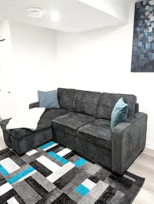 a gray couch in a living room with a rug at Basement Suite in Desrochers SW in Edmonton