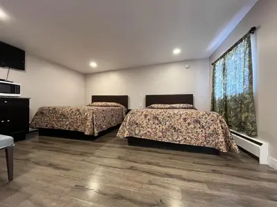 two beds in a room with two windows at Kluane Park Inn in Haines Junction