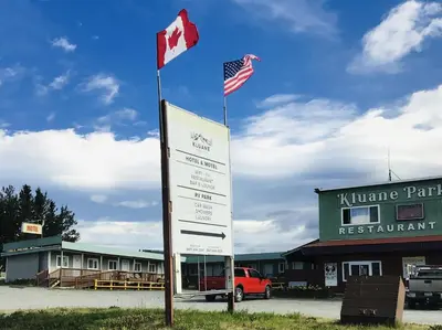 a sign in front of a building with two flags at Kluane Park Inn in Haines Junction