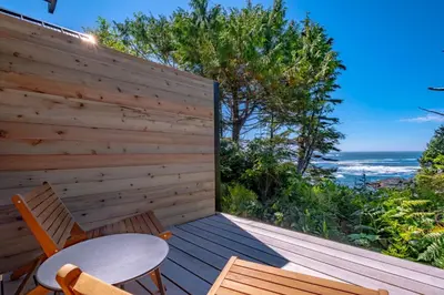 a wooden deck with a table and chairs on it at Fogged Inn in Ucluelet