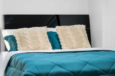 a bed with blue and white sheets and pillows at Cozy 2BR Suite with Kitchen, AC Near U of C, Winsport, Banff and Hospitals in Calgary