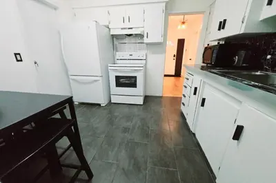 a kitchen with white appliances and a table in it at Private 2 BR Cozy Home Private Parking Free Sparkling and Goodies! 4 mins from Metrotown in Burnaby
