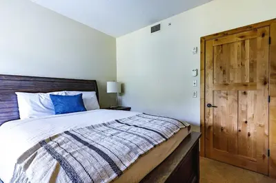 a bedroom with a bed and a wooden door at Creekside at Rundle Cliffs Lodge in Canmore