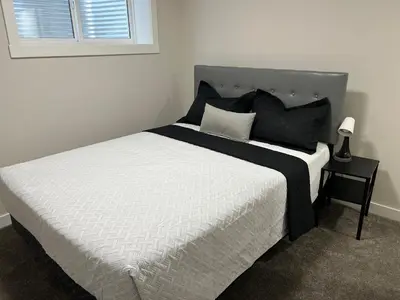 a bed with black and white sheets and a window at Little Heaven 2BR southwest Calgary in Calgary