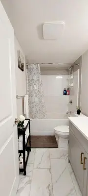 a white bathroom with a tub and a toilet at Little Heaven 2BR southwest Calgary in Calgary