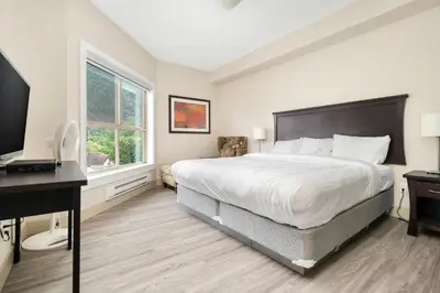 a bedroom with a bed and a desk and a television at Scenic 3BR unit in Harrison in Harrison Hot Springs
