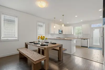 a kitchen with white walls and a wooden table and bench at Charming 3 Bedrooms Home with BBQ- Deck- Fenced yard-Near WEM & River Valley in Edmonton