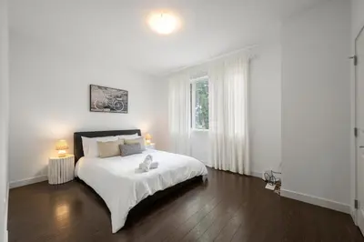 a white bedroom with a bed and a window at Charming 3 Bedrooms Home with BBQ- Deck- Fenced yard-Near WEM & River Valley in Edmonton