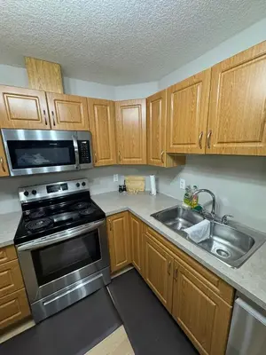 a kitchen with wooden cabinets and a stove and a sink at The Bloom Haven in Edmonton