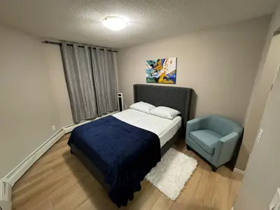 a bedroom with a bed and a blue chair at The Bloom Haven in Edmonton