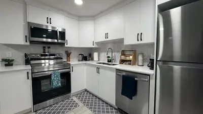 a kitchen with white cabinets and a stainless steel refrigerator at Cozy & Quiet Calgary 2BR Suite in Calgary
