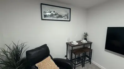 a living room with a chair and a table and a television at Cozy & Quiet Calgary 2BR Suite in Calgary