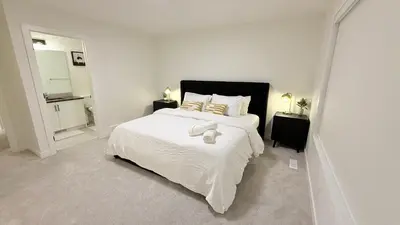 a white bedroom with a large bed with white sheets at Casa Koko in Calgary