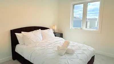 a bedroom with a bed with white sheets and a window at La Maison de Koko in Calgary
