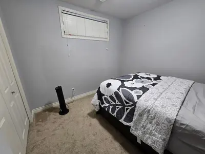 a white bedroom with a bed and a window at Basement Suite Private Entry Fort McMurray in Fort McMurray
