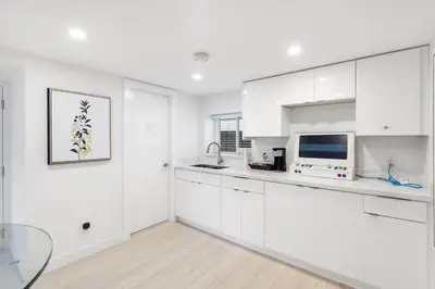 a white kitchen with white cabinets and a glass table at Callister BNB in Vancouver