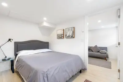 a white bedroom with a bed and a couch at Callister BNB in Vancouver