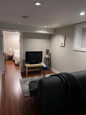 a living room with a flat screen tv and a bed at Vancouver Comfort Home 10 min to YVR airport, Close to Downtown in Vancouver