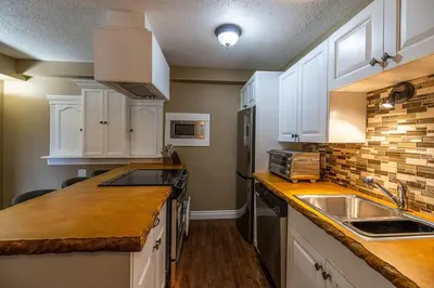 a kitchen with white cabinets and a sink at Elowen Suites Downtown in Drumheller