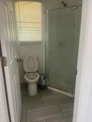 a bathroom with a toilet and a glass shower at one private room in Victoria