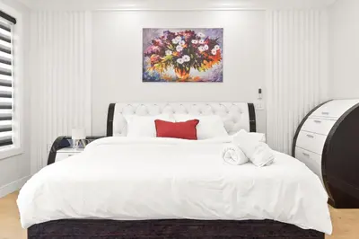 a bedroom with a large white bed with a painting on the wall at Spacious 6BR Entire Home Sleeps 14 Private Parking Pet-Friendly Near Vancouver in Surrey