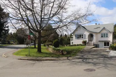 a white house on a street with a stop sign at Victoria Gorge Waterway Vacation Home in Victoria