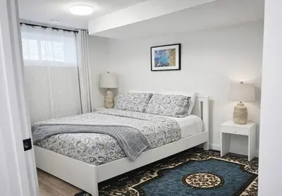 a white bedroom with a bed and a window at 1 BR suite near WEM, with fast WiFi and Equipped kitchen in Edmonton