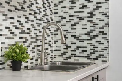 a sink in a kitchen with black and white tiles at Bright 2BR Suite Near YYC & Mall in Calgary
