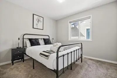 a white bedroom with a bed and a window at Large House with Billiards, 5 Bedrooms, Garage Parking & Free Banff Access in Calgary