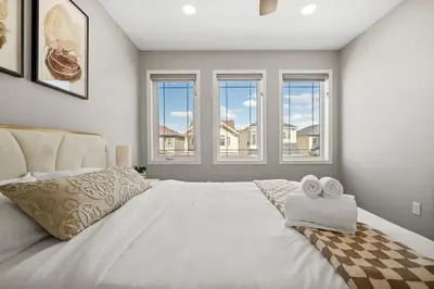 a bedroom with a large white bed with two towels at Large House with Billiards, 5 Bedrooms, Garage Parking & Free Banff Access in Calgary