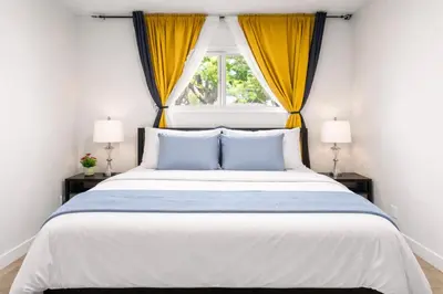 a bedroom with a large bed with yellow curtains at Bright 3-Bed Retreat Near the Zoo and Downtown in Calgary