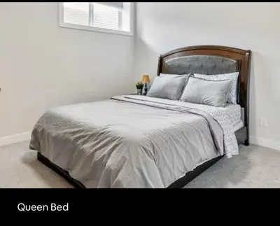 a white bed with a wooden headboard in a bedroom at Brand new suite with parking pad at the back in Calgary