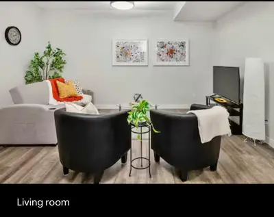 a living room with two black chairs and a couch at Brand new suite with parking pad at the back in Calgary