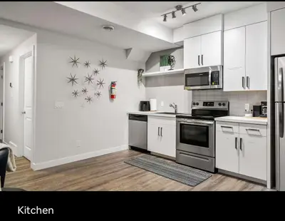 a kitchen with white cabinets and silver appliances at Brand new suite with parking pad at the back in Calgary