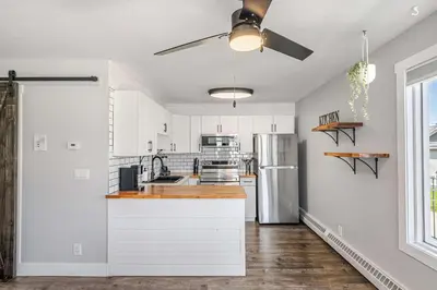 a kitchen with white cabinets and a ceiling fan at Lakefront Lookout 1BR Condo on Lakeshore Drive in Sylvan Lake