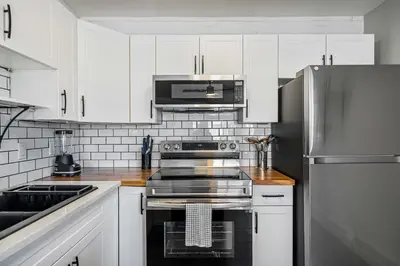 a kitchen with white cabinets and a stainless steel refrigerator at Lakefront Lookout 1BR Condo on Lakeshore Drive in Sylvan Lake