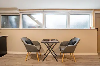 two chairs and a table in a room with windows at The Rosemead Suite in Kelowna