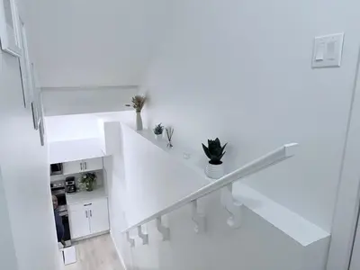 a white staircase in a white apartment with plants at Cozy 2BR Basement Rosenthal Stay by WEM with private entrance in Edmonton