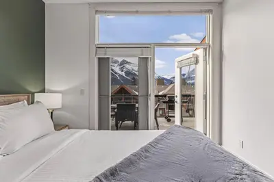 a bedroom with a bed and a large window at Amazing mountain Views 3BR Penthouse with private Balconies in Canmore