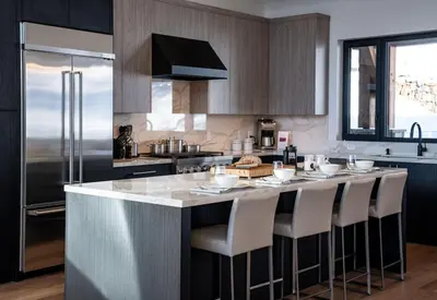 a kitchen with a large island with white bar stools at Sitka Spruce Mountain Chalet in Revelstoke