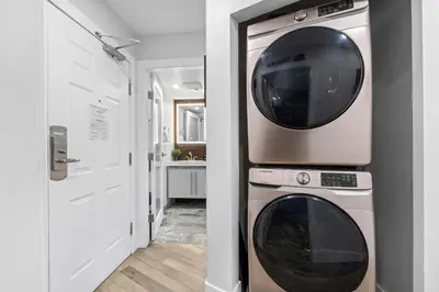 a laundry room with a washer and dryer next to a door at 1BR and Den in Marketplace Lodge, Village Location, Mountain Views, Gas Fireplace, Parking in Whistler