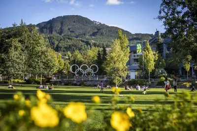 a park with people sitting in the grass with the olympic rings at 1BR and Den in Marketplace Lodge, Village Location, Mountain Views, Gas Fireplace, Parking in Whistler
