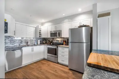 a kitchen with white cabinets and a stainless steel refrigerator at Lakefront Suite on Shawnigan Lake in Shawnigan Lake