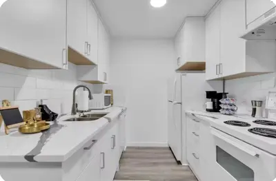 a white kitchen with a sink and a stove at 17th Ave Cozy Nest in Downtown Calgary with Parking in Calgary