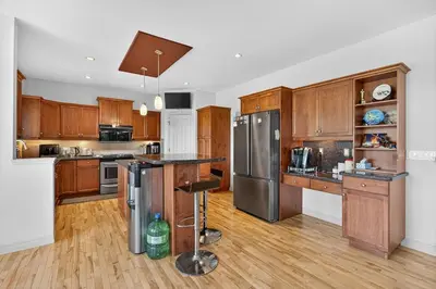 a kitchen with wooden cabinets and stainless steel appliances at Luxury Home with 5 BR, 9 Beds, 4BA, sleep 12, AC, Crib in Calgary