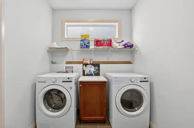 a laundry room with two washing machines and a window at Luxury Home with 5 BR, 9 Beds, 4BA, sleep 12, AC, Crib in Calgary