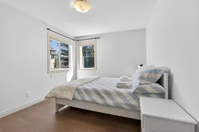 a white bedroom with a bed and a window at Luxury Home with 5 BR, 9 Beds, 4BA, sleep 12, AC, Crib in Calgary