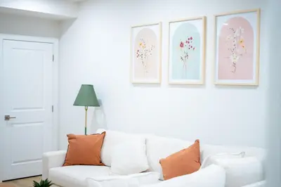 a white couch in a living room with three pictures on the wall at Modern Luxury Stay - Airport, Banff, Rockies Route in Calgary